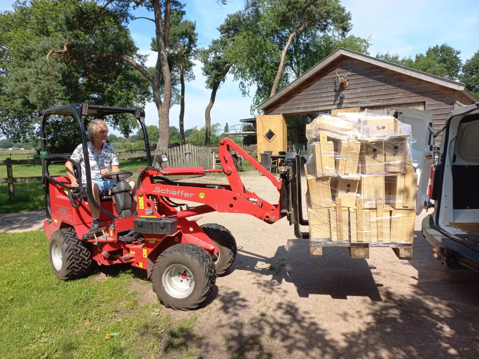 Opa Teunis Ruiter brengt met de minitractor een pallet hout naar de bus, klaar om verwerkt te worden tot vogelhuisjes