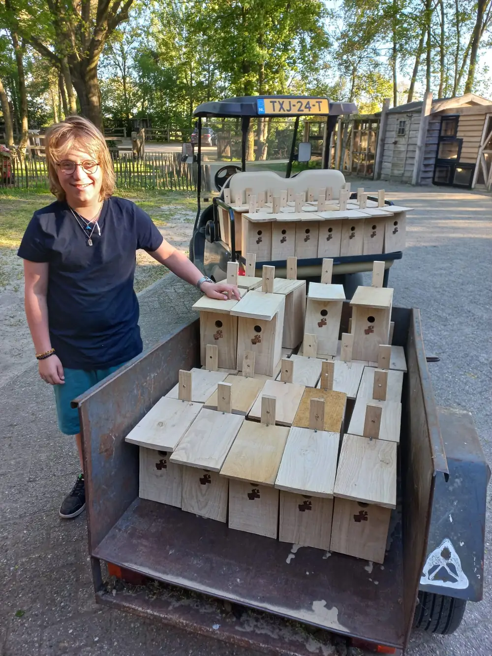 Jace naast een wagentje vol vogelhuisjes